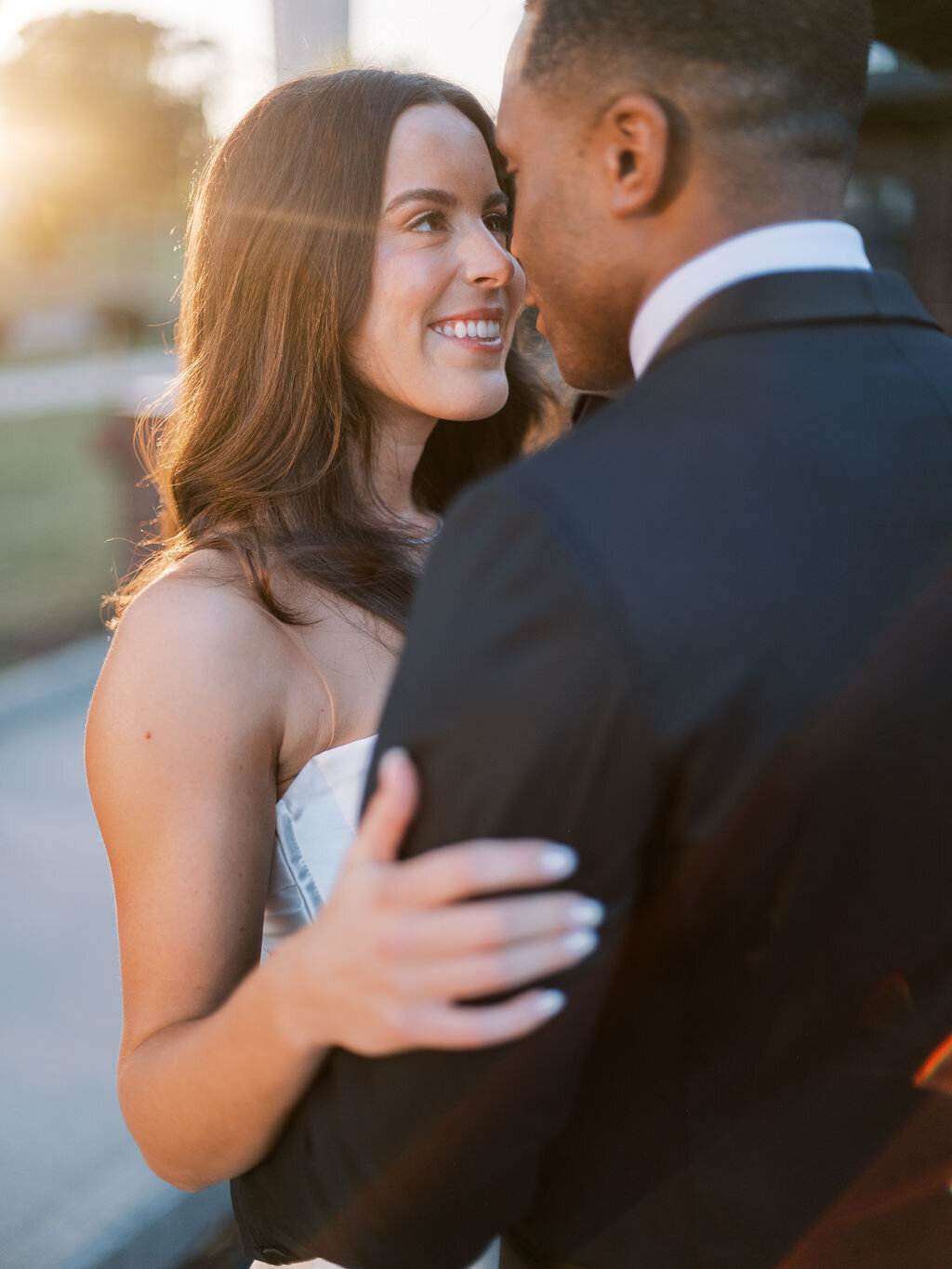 The bride and groom share an intimate moment, smiling as the sunlight softly illuminates them.