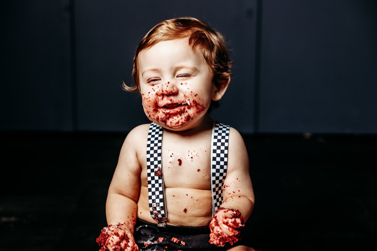 One year old eating cake during a studio photoshoot.