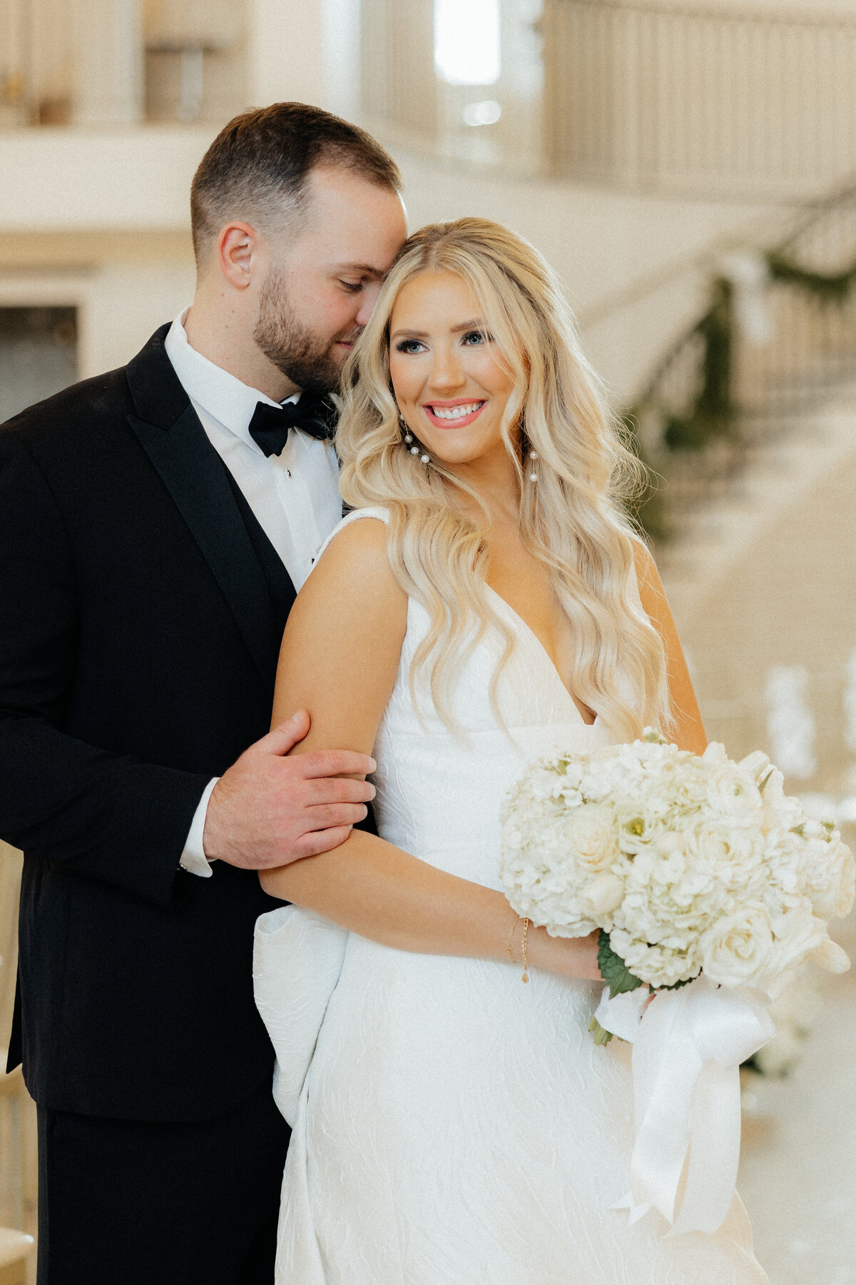 The bride smiling while the groom leans in to her.