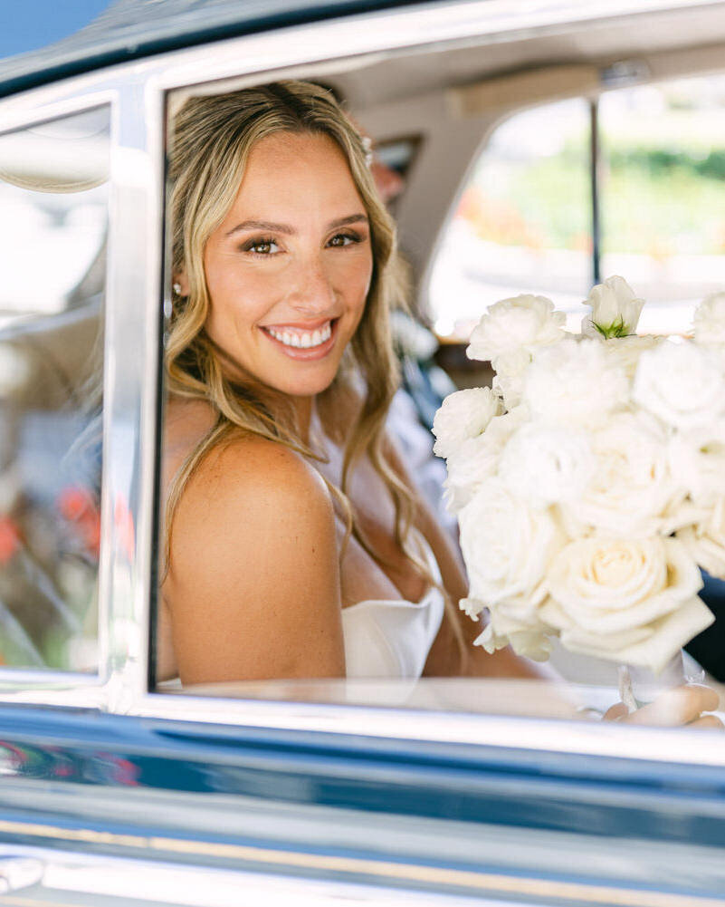 This elegant portrait captures the bride smiling as she looks at the camera from inside a luxury Rolls Royce outside the VIP entrance of the Banff Springs Hotel. The luxurious setting and joyful expression perfectly reflect the sophistication and excitement of her wedding day.