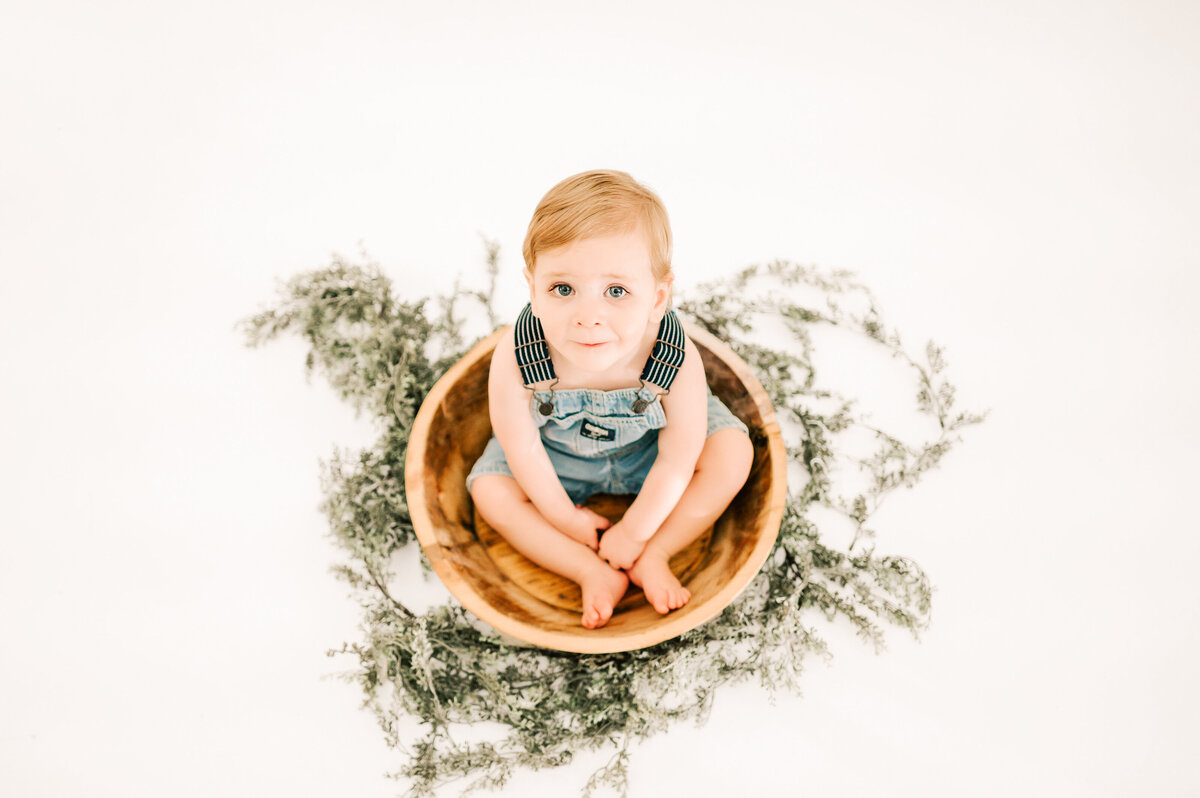 overhead view of toddler boy sitting in bowl during 1st birthday photography session in Springfield MO