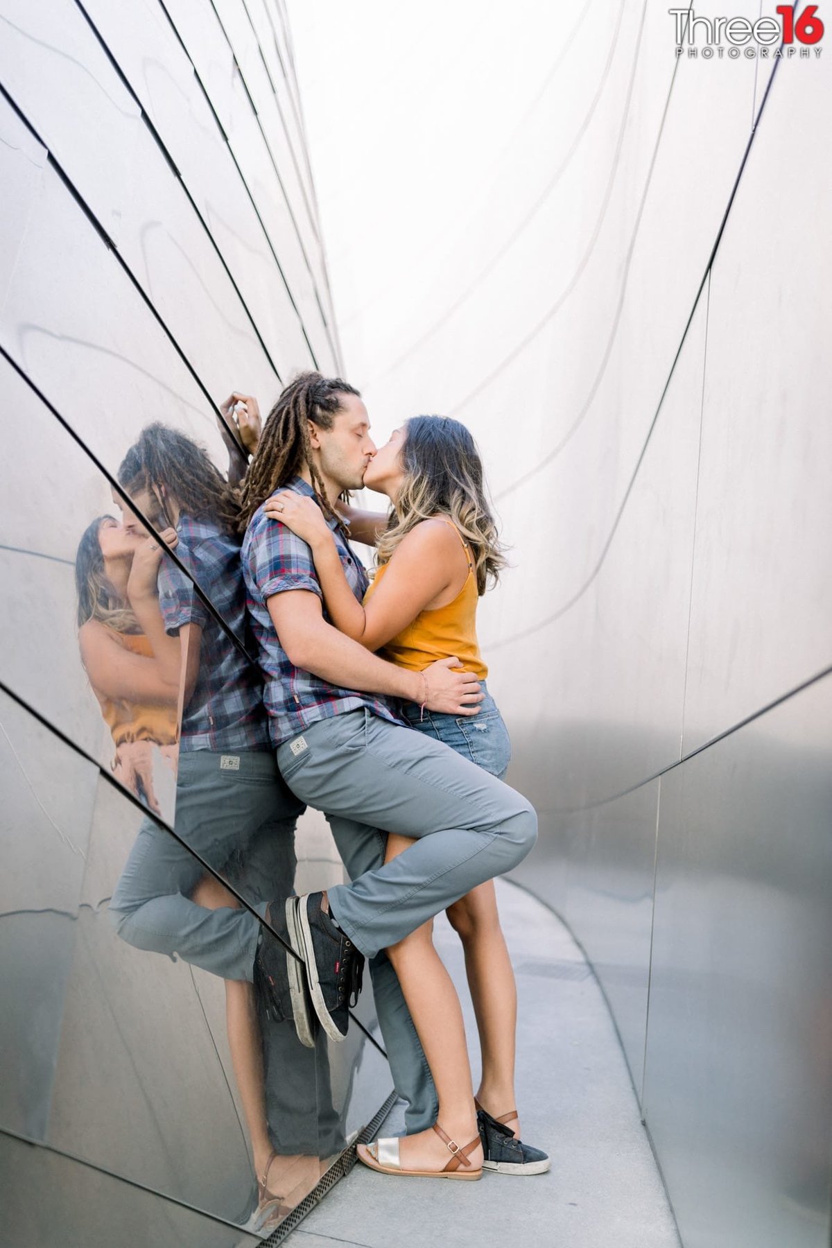 Engaged couple share a kiss amongst the reflective walls at the Walt Disney Concert Hall