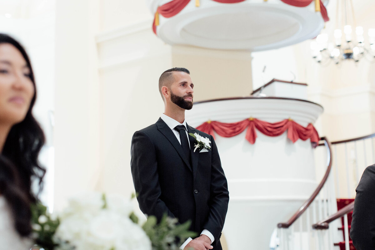 Groom tearing up waiting for his bride at the aisle.