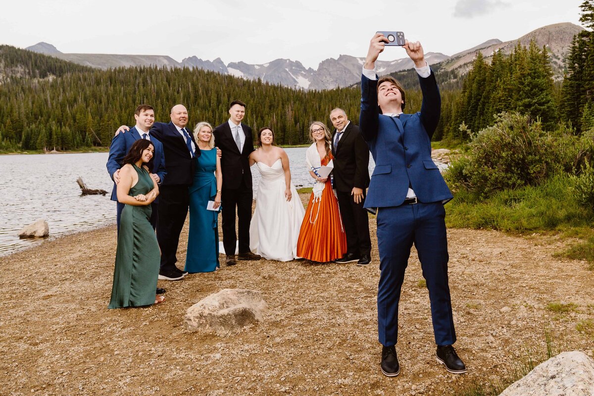 Wedding couple posing with family for a group selfie by the lake at Brainard Lake Recreation Area in Colorado.