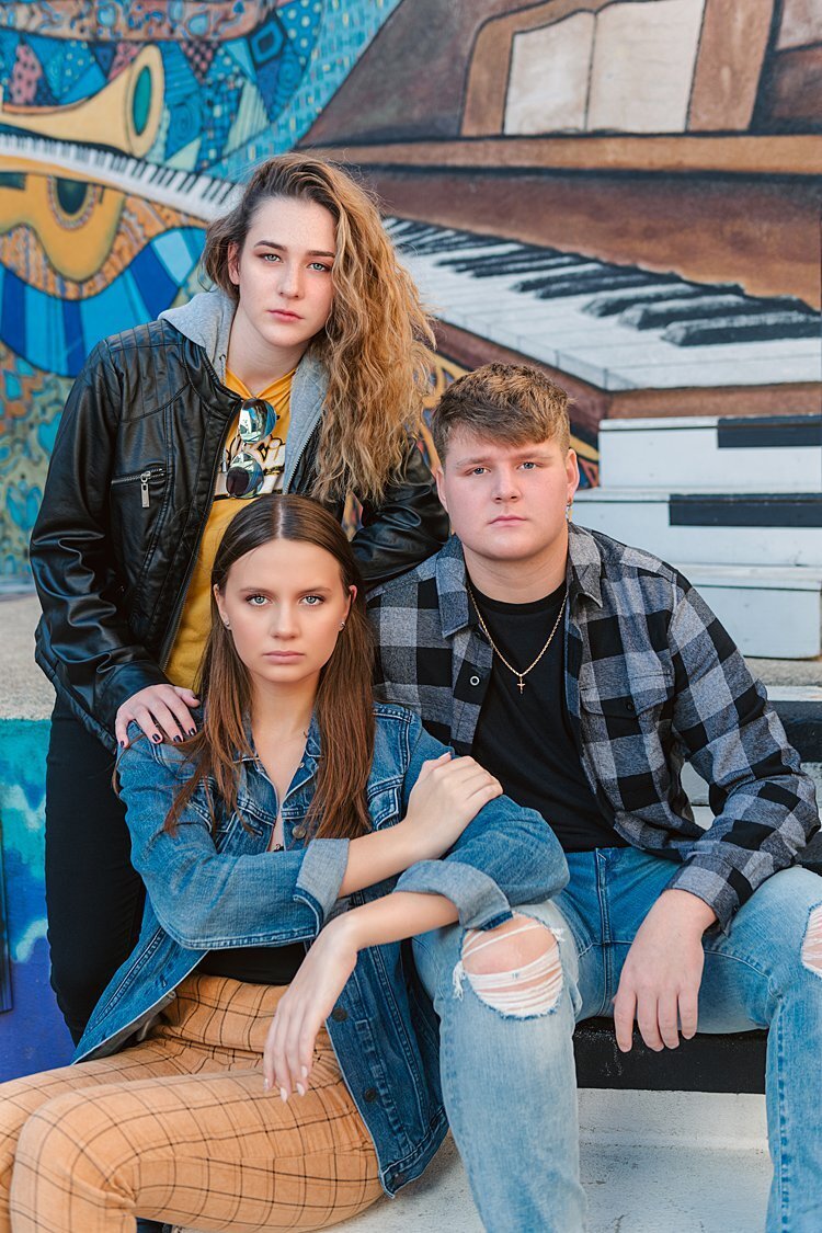 2 senior girls and 1 senior guy seated on piano key steps