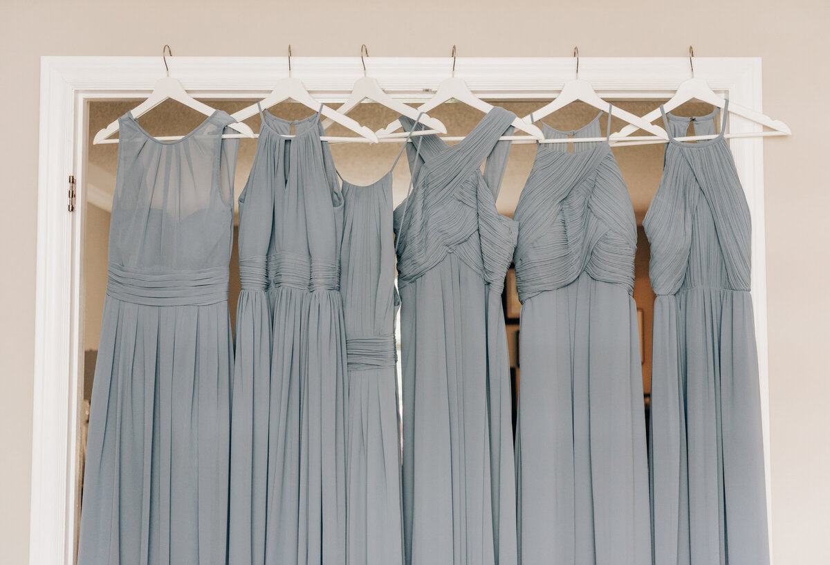 Light blue bridesmaids dresses hung along doorway while getting ready for wedding