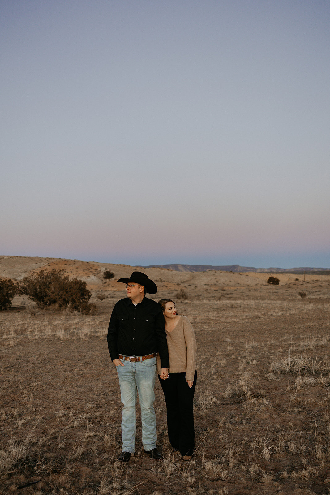 engaged couple standing together with a wide desert view