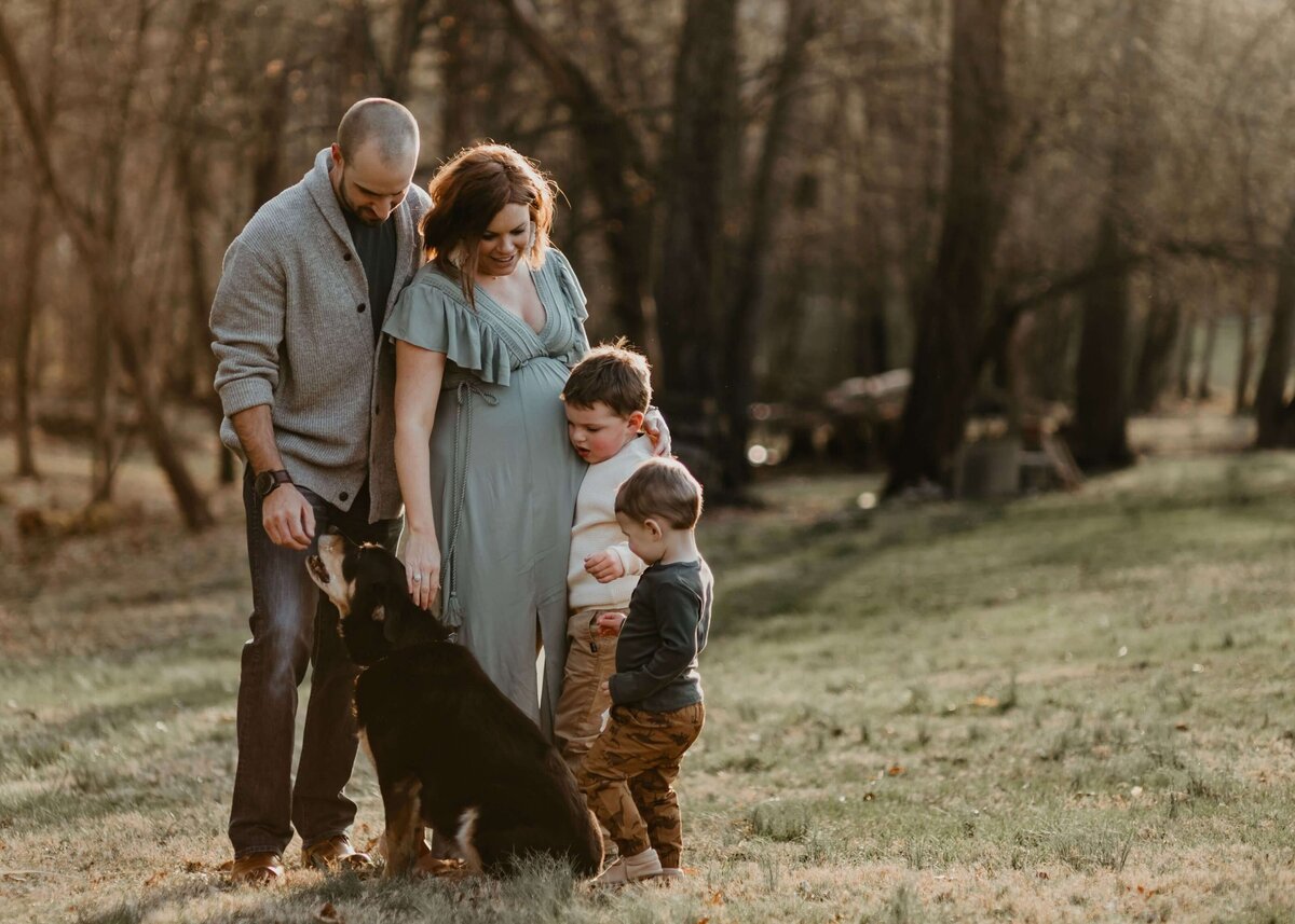 A family poses with their dog in a field, captured by a Pittsburgh maternity photographer.