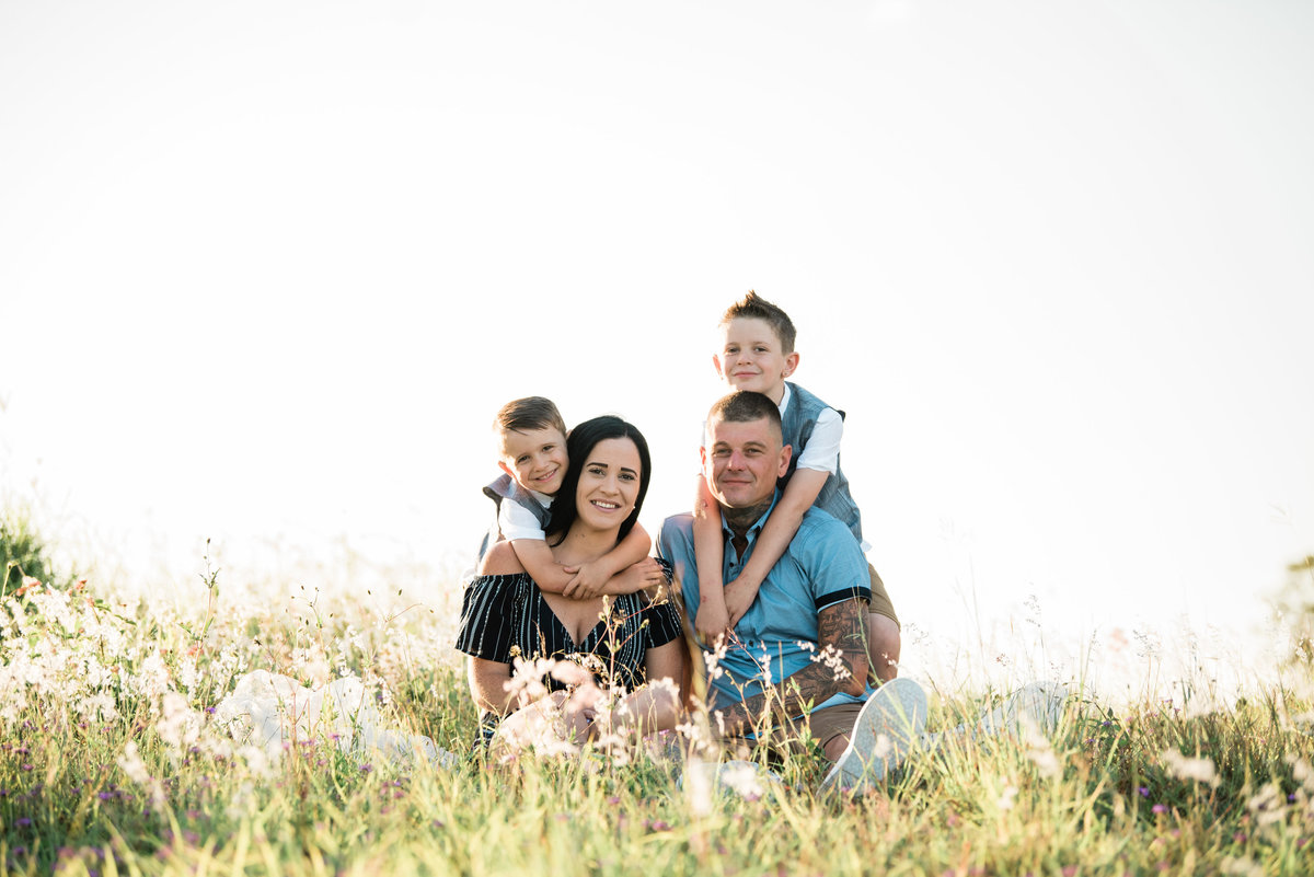 family-sitting-in-long-grassy-field-at-sunset-lead-images-3