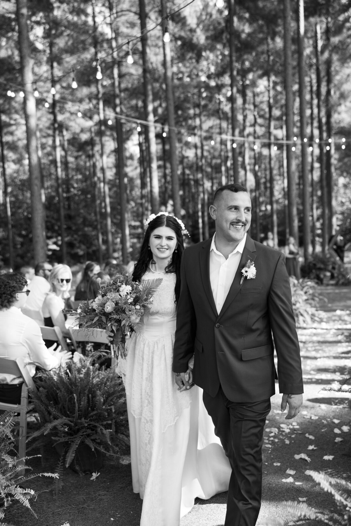 A newlywed couple holding hands and smiling as they leave their wedding ceremony