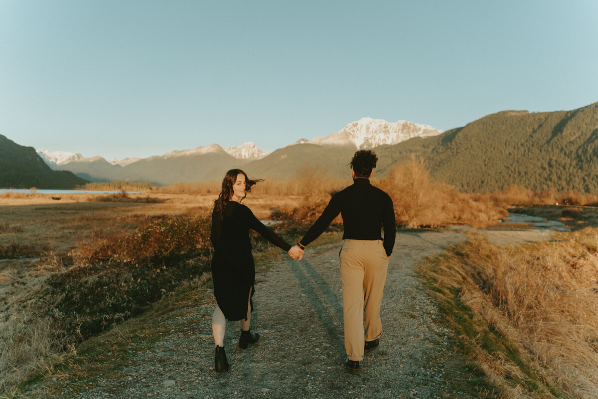 timeless engagement photo of a girl and boy walking off into the distance but girl looks back