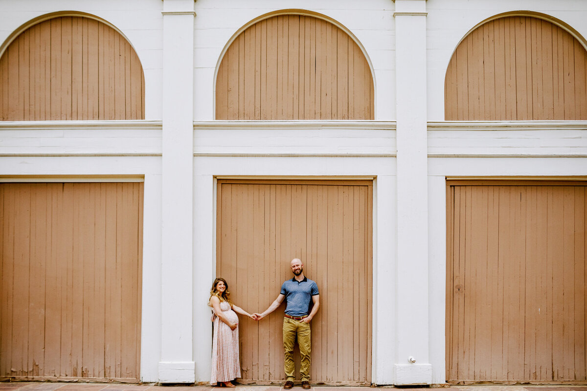 boulder maternity photo with woman in pink dress holding her baby bump and her partner's hand