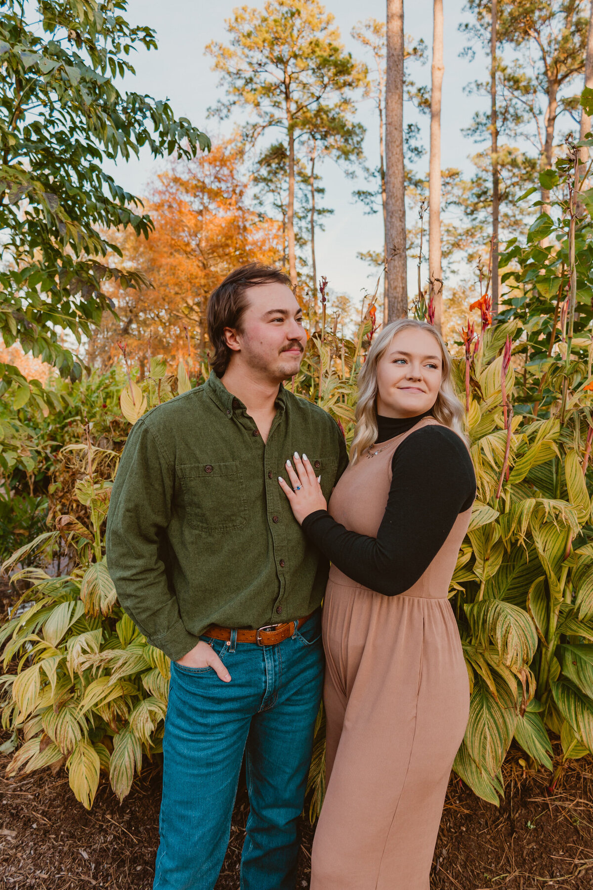 Engagement proposal photo of Josh and his partner at Mercer Botanical Garden in Humble, Texas. The couple stands together, surrounded by lush greenery, with Josh wearing a green shirt and his partner in a soft peach dress. Captured by ShutterUp Photography, Houston wedding and engagement photographer.