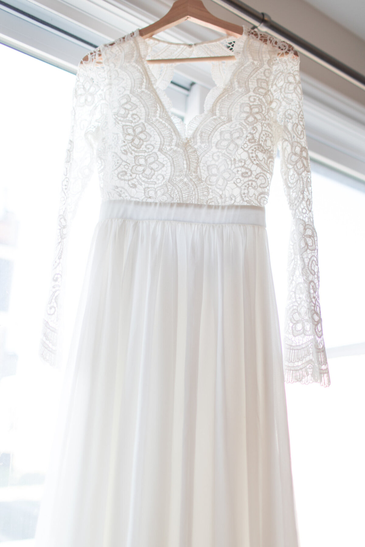 Step into the enchanting world of bridal elegance with this mesmerizing capture by Ottawa Wedding Photographer, Lauren Duffy. The ethereal glow of natural light gently caresses a suspended wedding dress in front of a picturesque window, creating a moment of pure romance. Lauren Duffy Photography skillfully embraces the interplay of light and fabric, infusing a timeless allure into this scene. Elevate your wedding experience with the artistry of Ottawa's premier photographer, as Lauren Duffy expertly captures the ethereal essence that defines your journey to 'I do.'