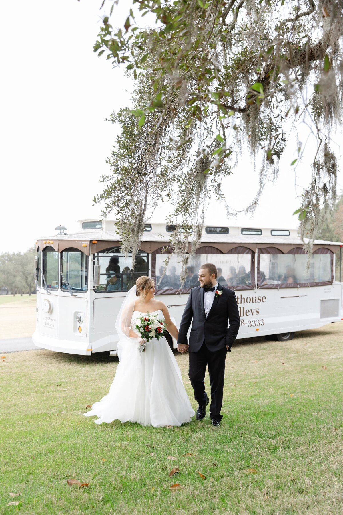 a bride and groom holding hands in front of a trolley bus at Saint Simons Island