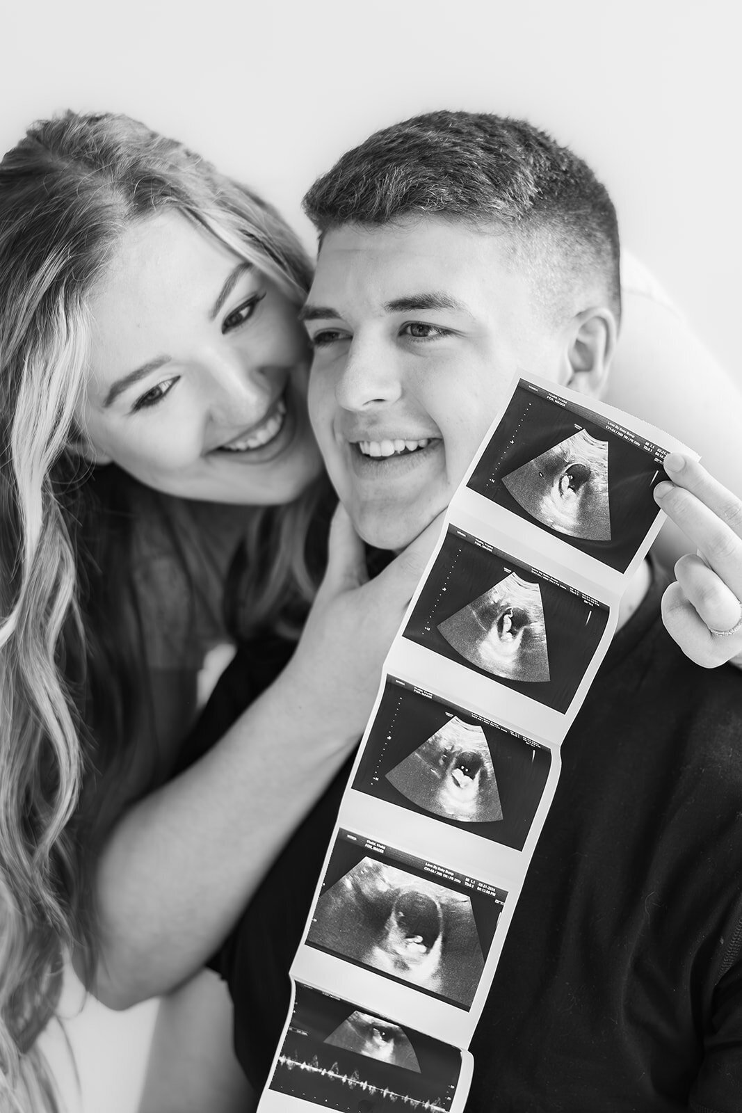 Couple smiling next to their ultrasound phhotos