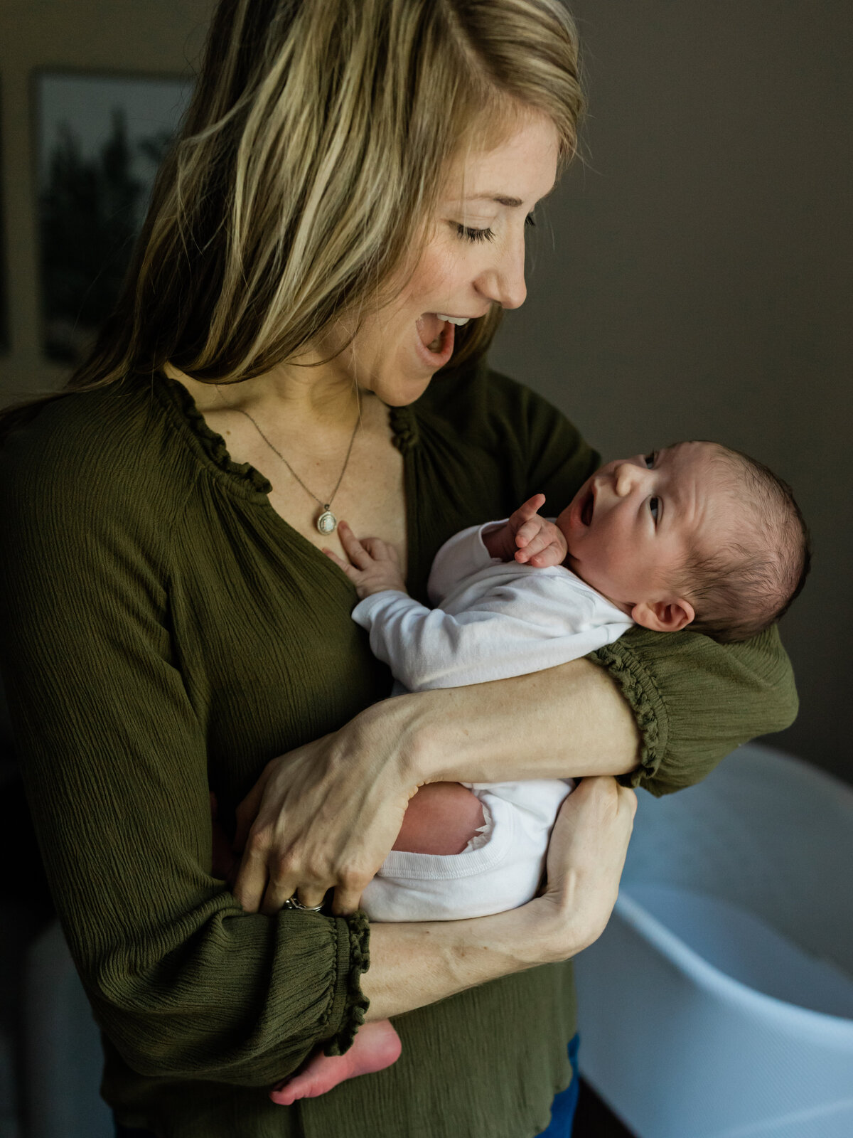 mom and dad sitting on couch holding newborn baby boy for in home lifestyle session cleveland newborn photographer
