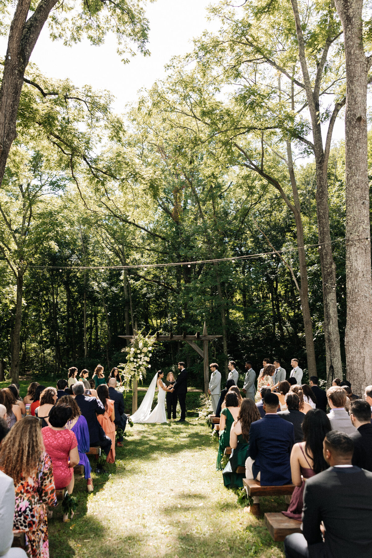 Bride and Groom standing under a floral arch during their wedding ceremony at Junebug Resort.