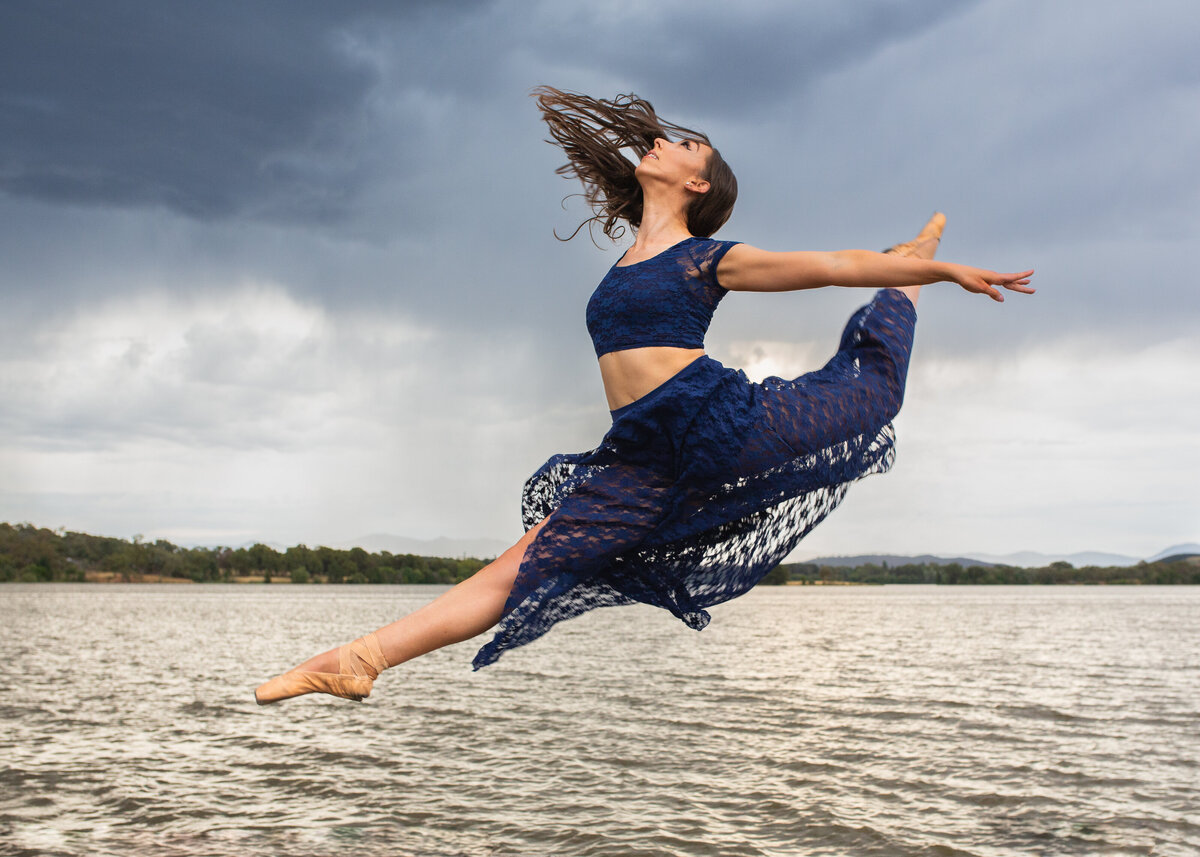 Dancer jumping by Canberra lake in storm