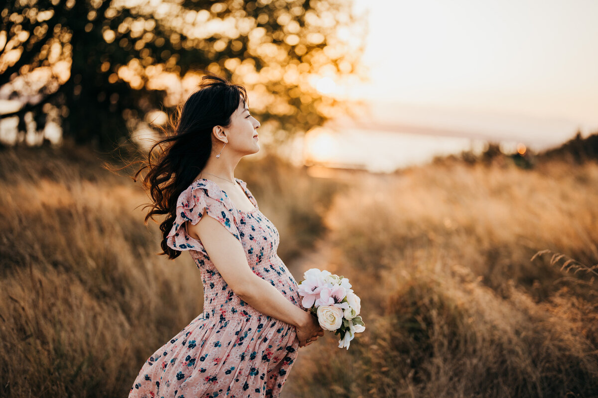 seattle-pregnant-woman-holding-bouquet-at-discovery-park-golden-hour
