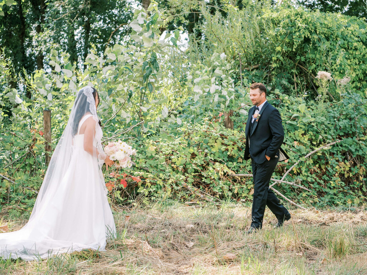 A bride and groom have their first looks outdoors before their luxury backyard wedding.