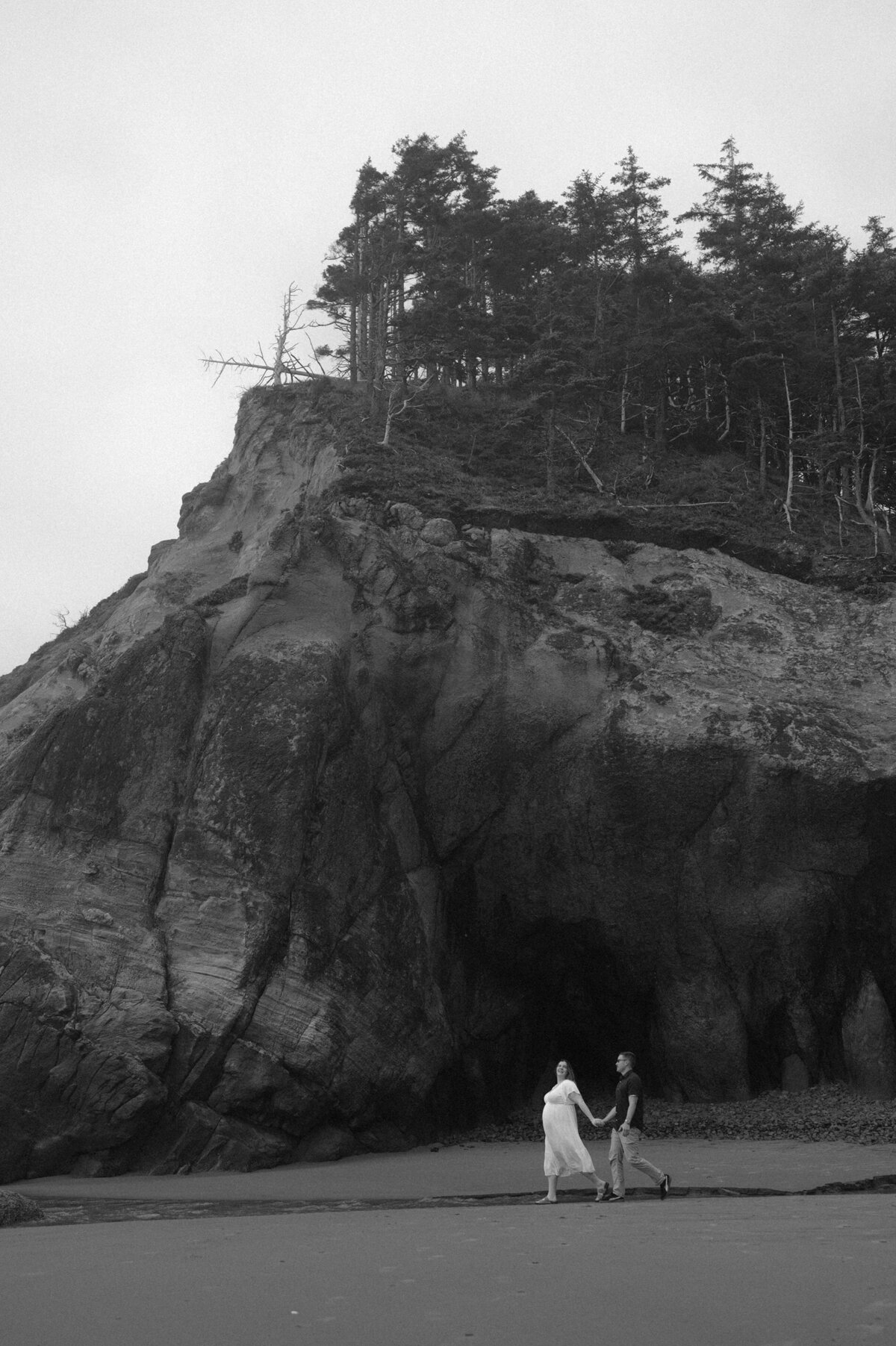 bride and groom hold hands and walk along the beach at the Oregon coast