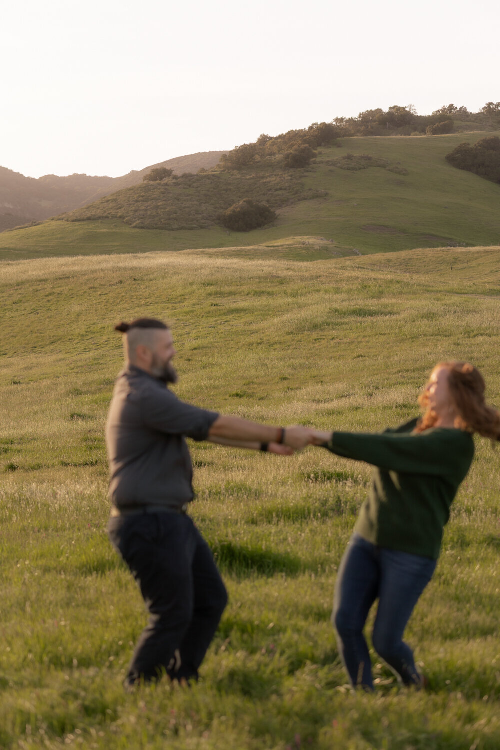 Couples Engagement Photos candid dancing in green field  on the Central Coast in San Luis Obispo 