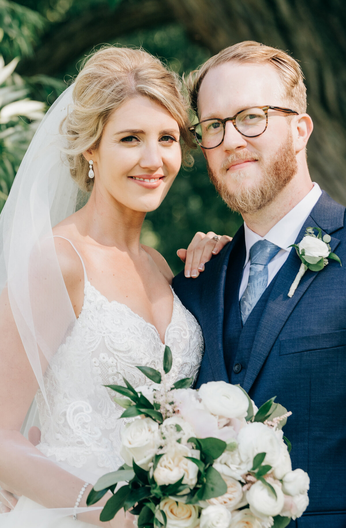 Elegant portrait of bride and groom holding bouquet of white roses and eucalyptus