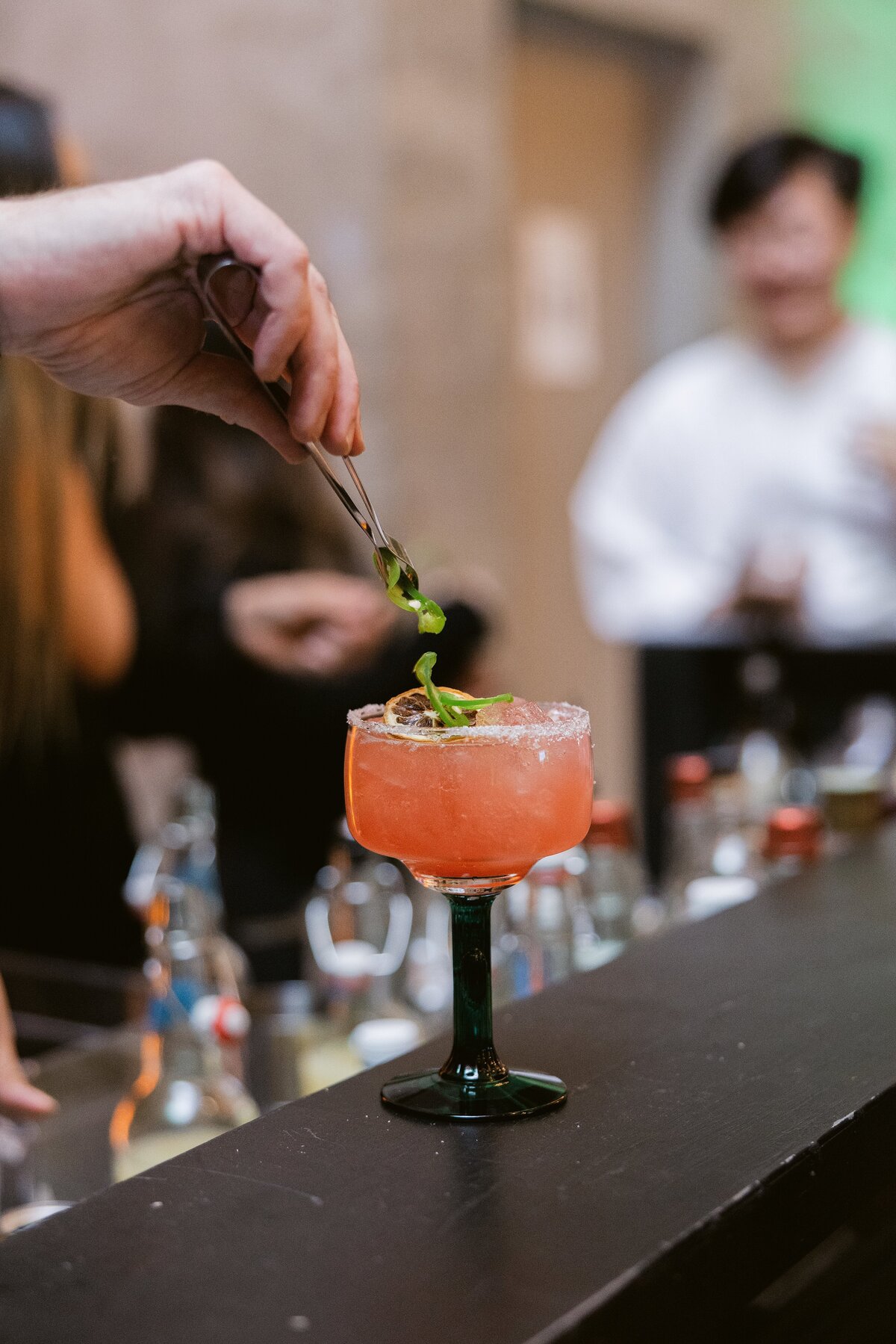 bartender adds garnish to cocktail