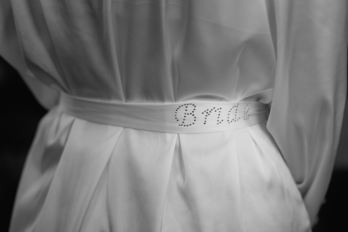 Das Model trägt einen Satin-Morgenmantel mit der Aufschrift "Bride" aus Strasssteinen auf dem Gürtel.