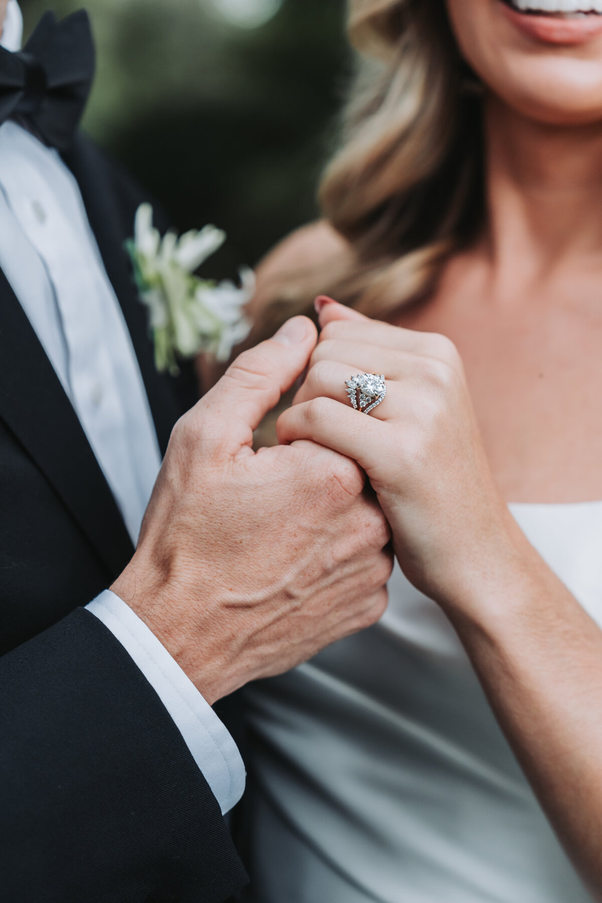 Groom holds bride's hand and shows wedding ring