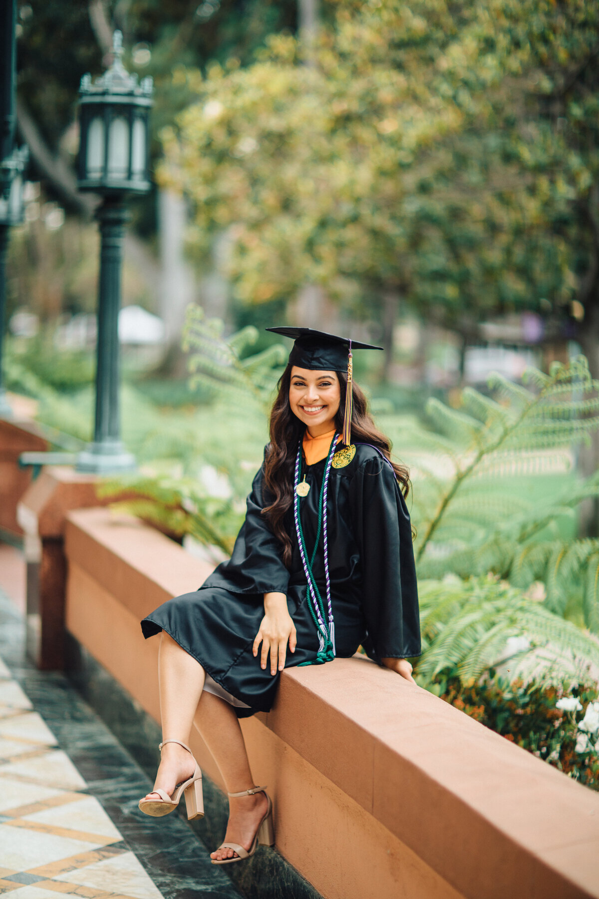 Graduation Portrait Of Young Woman In Black Toga Sitting On The Hallway Los Angeles