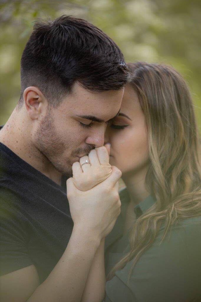 Sacramento wedding photographer, philippe studio pro photographs man kissing engaged woman's ring hand during an engagement shoot.  Both have their eyes closed and look very romantic.