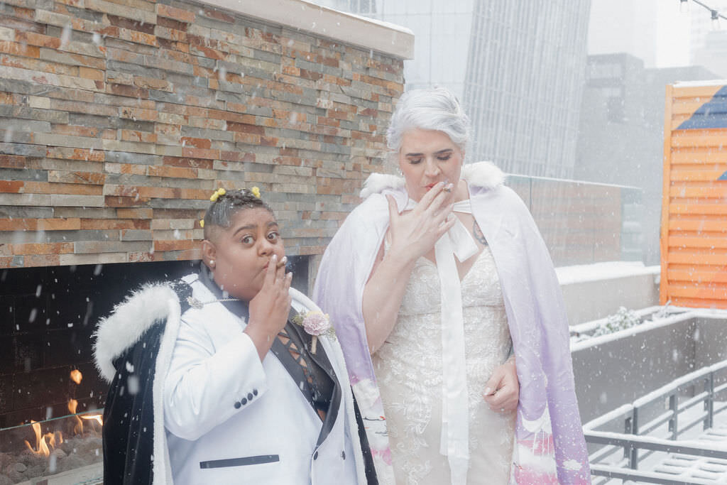 A newlywed couple smoking outside in the snow.