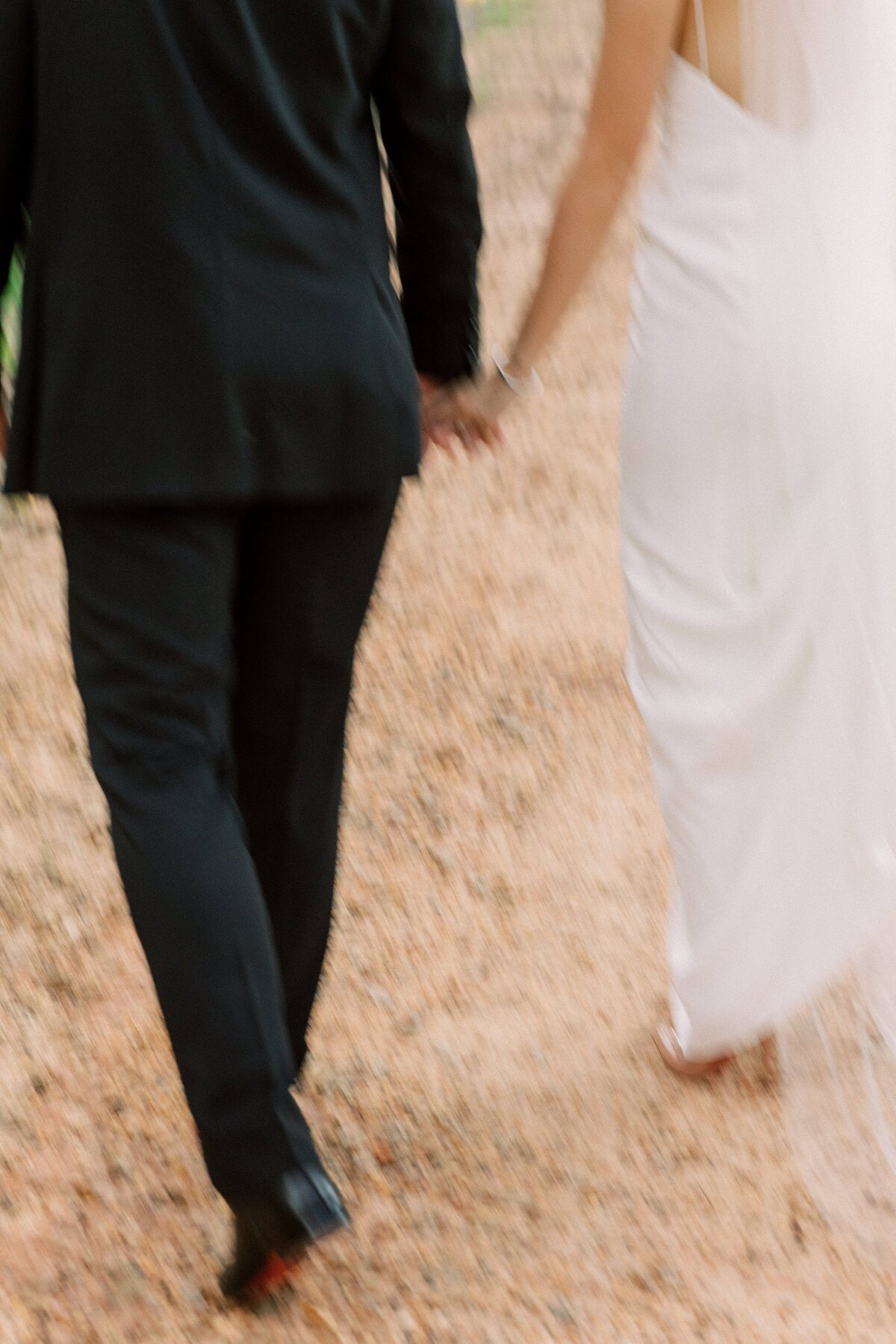 Bride and groom walk away holding hands