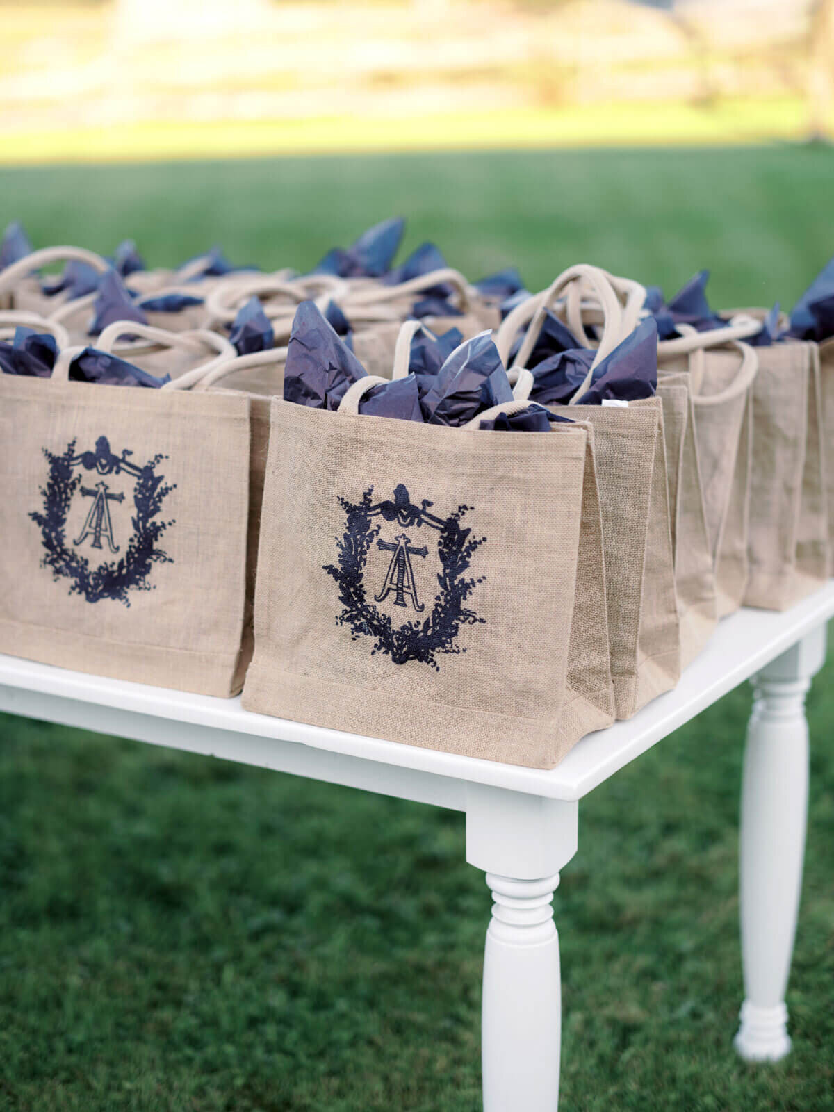Wedding give-away brown bags with blue logo and blue package inside, are on a table at Lion Rock Farms, CT. Image by Jenny Fu Studio