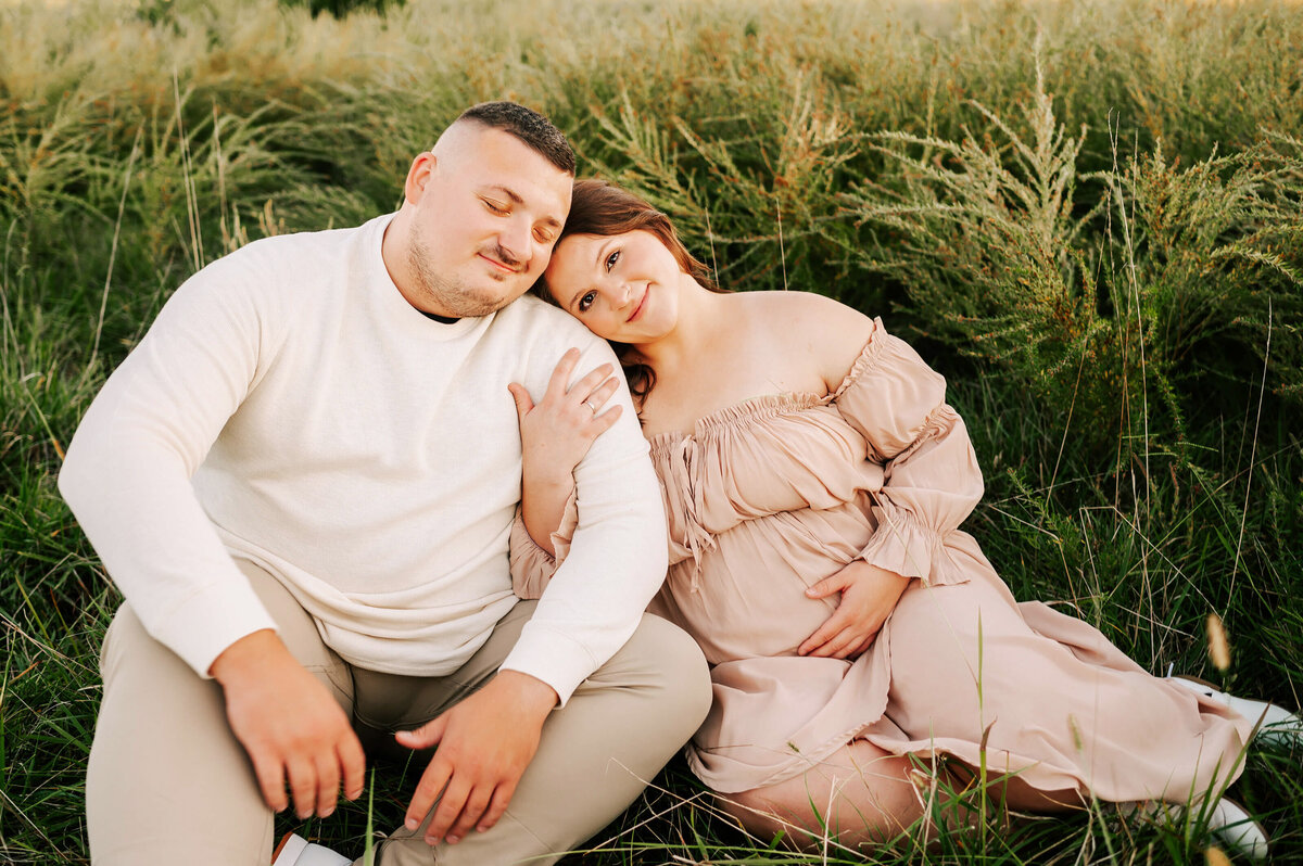 Branson MO maternity photographer The XO Photographer captures pregnant mom leaning on husbands shoulder in field