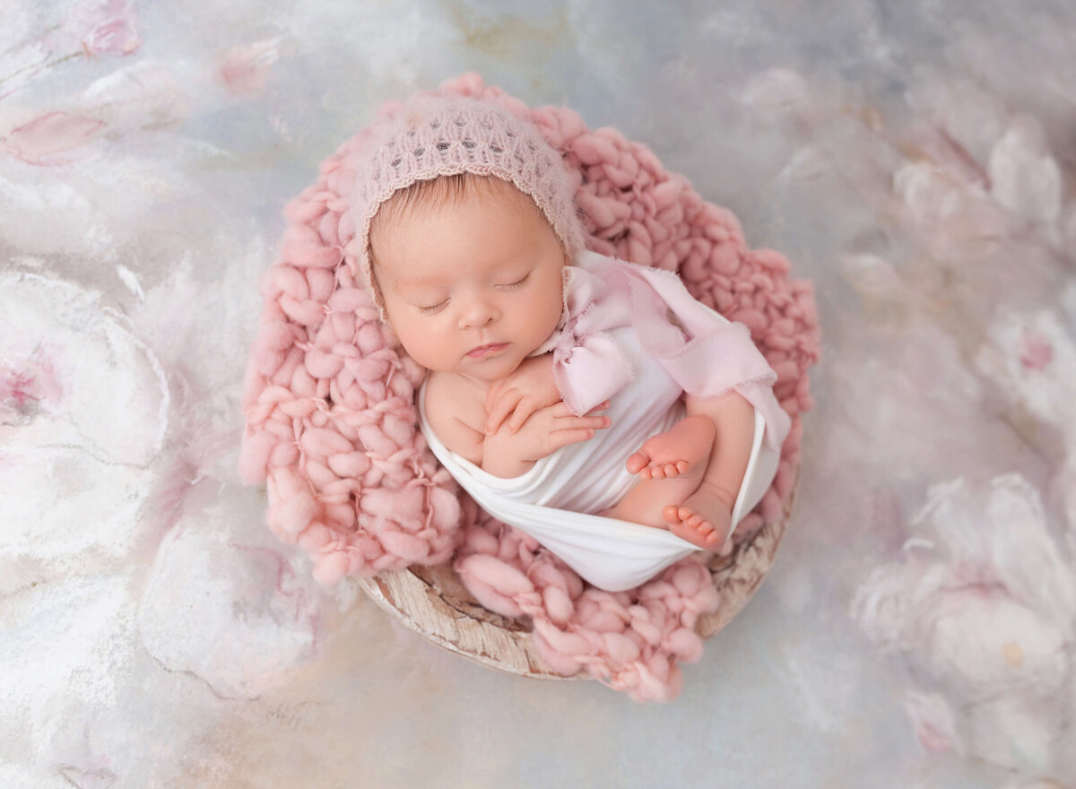 Baby girl sleeping on pink blanket with a pink hat