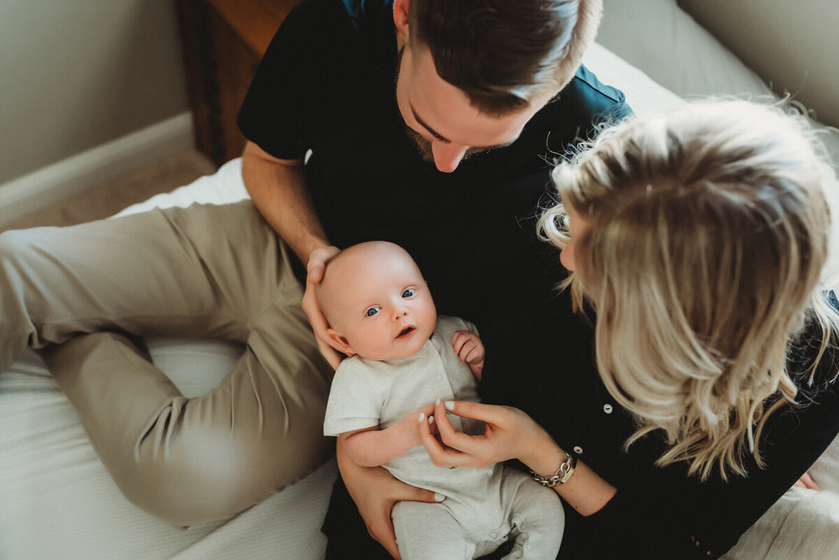 mom and dad holding baby boy while baby looks at camera