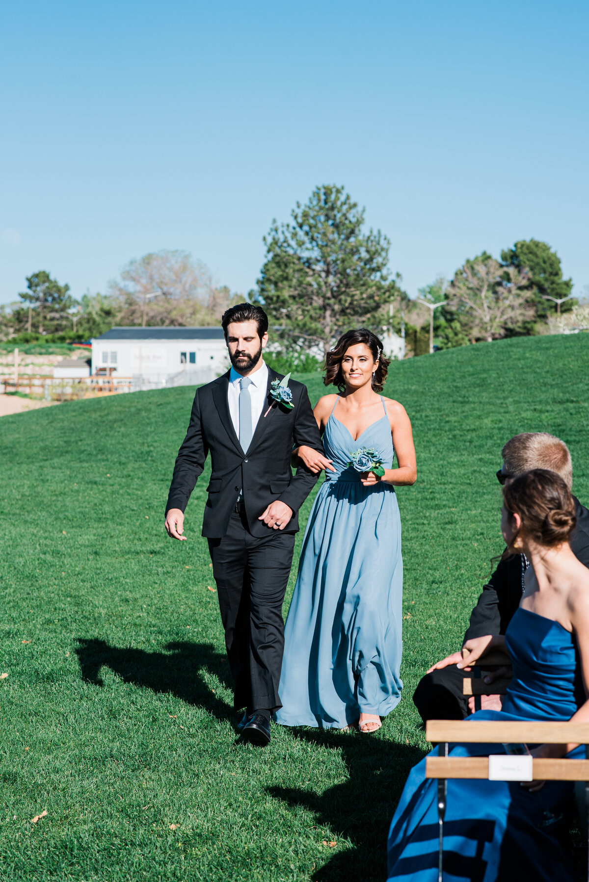 A maid of honor and best man walk down the isle together for a wedding at The Oaks captured by denver wedding photographer, kb radiant photography