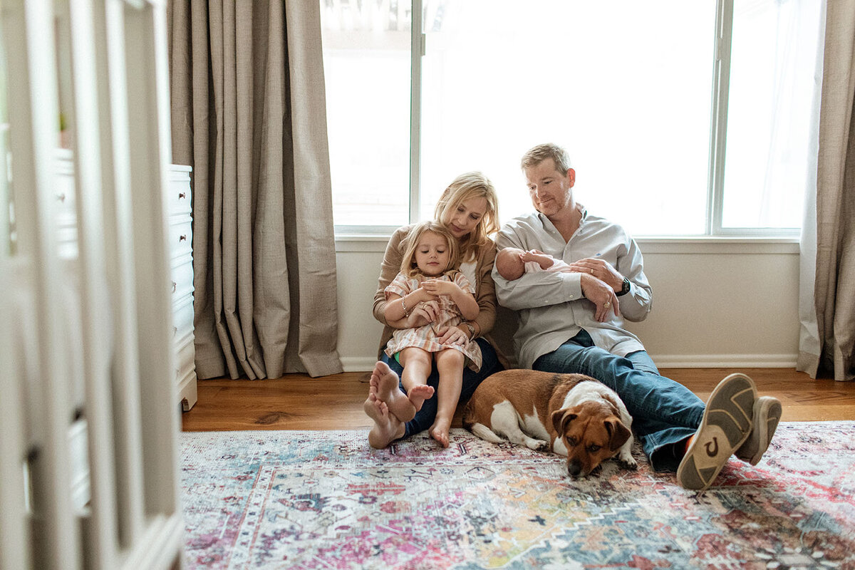 Family relaxing on floor with beloved dog at home - Sara James captures pet-inclusive family moments and household connections during lifestyle photography sessions in San Antonio Texas residential settings