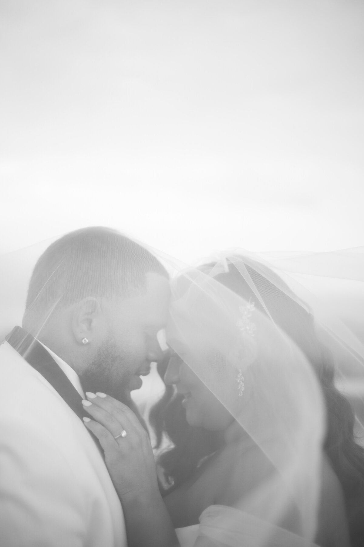 Bride and groom closing their eyes with bride's veil over them