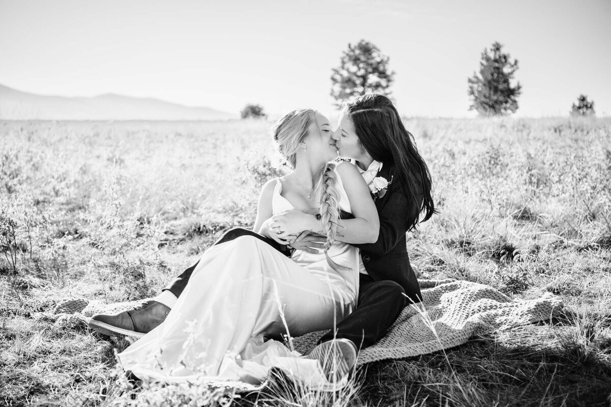 Same sex Missoula couple on wedding day kissing on a blanket, Blue Mountain, Missoula