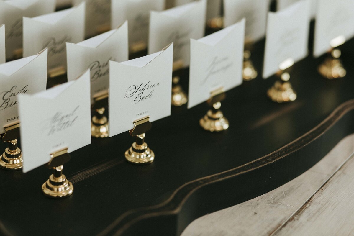 White squared place cards with black cursive font on gold place card holders.
