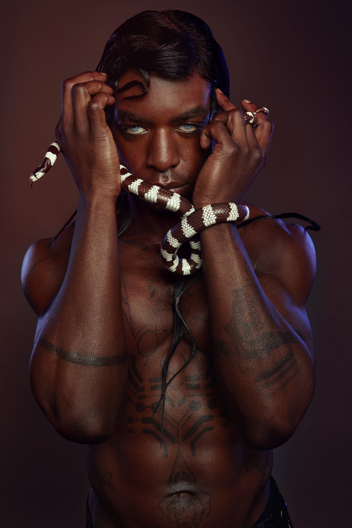 Artistic portrait of Jonzu wearing layered pearls and showcasing his tattoos, photographed by Ylva Erevall.