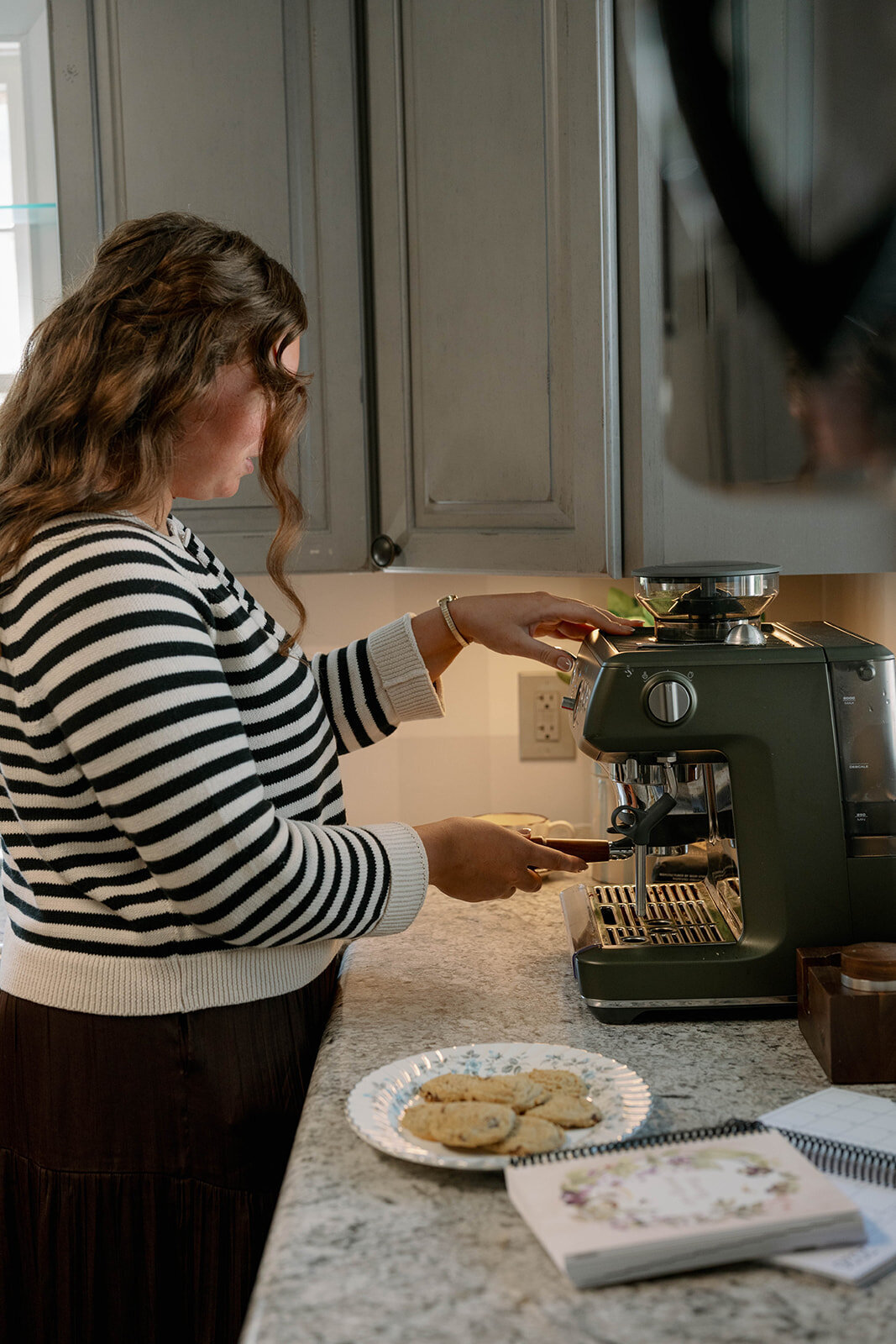 Close-up of a woman making coffee using an espresso machine during the planner company branding session.