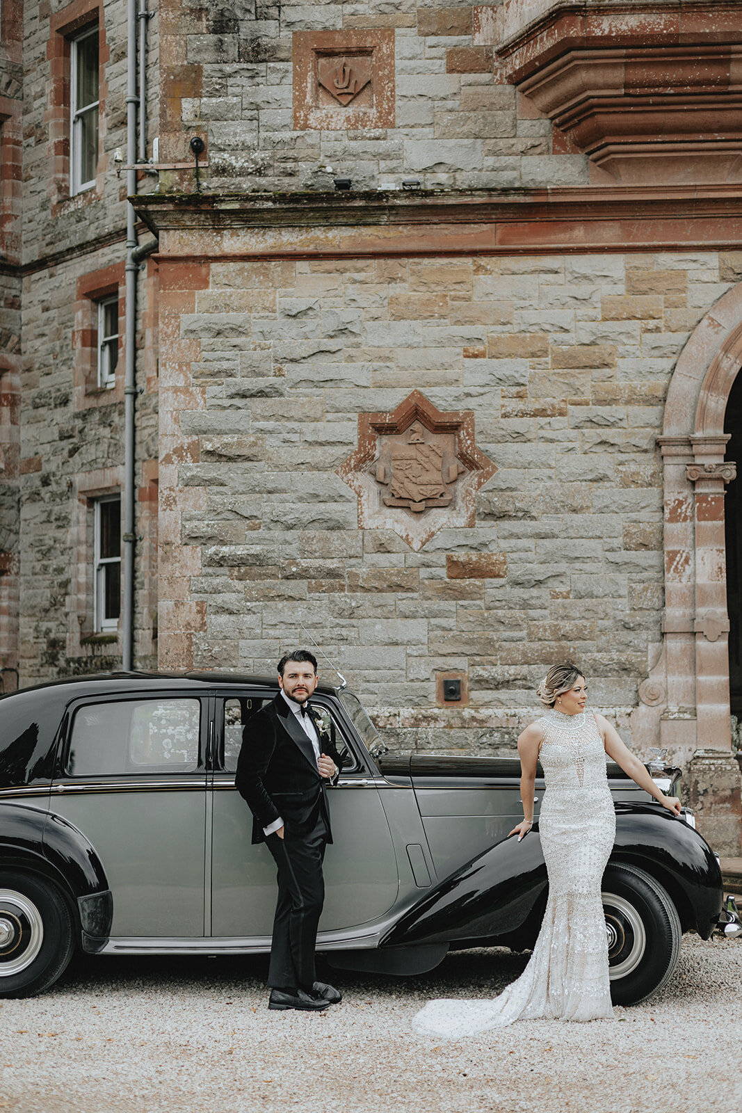 Bride and groom leaning against old car in Ireland
