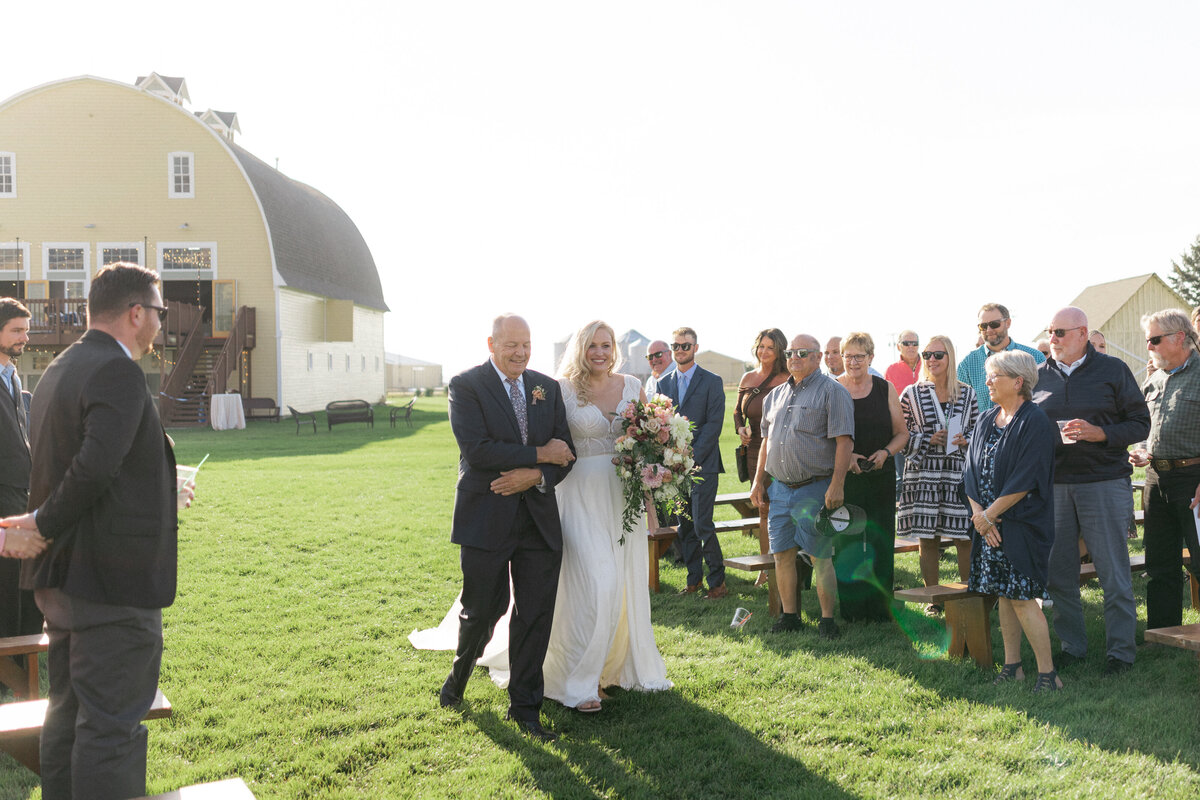 Father walks bride down the aisle at outdoor ceremony