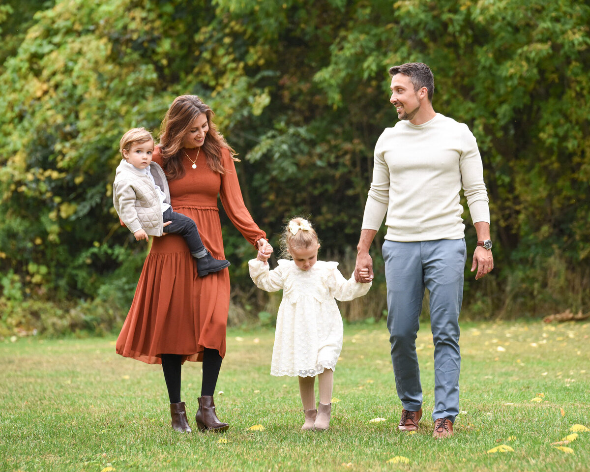 Mom in orange dress holding daughter's hand for family portrait
