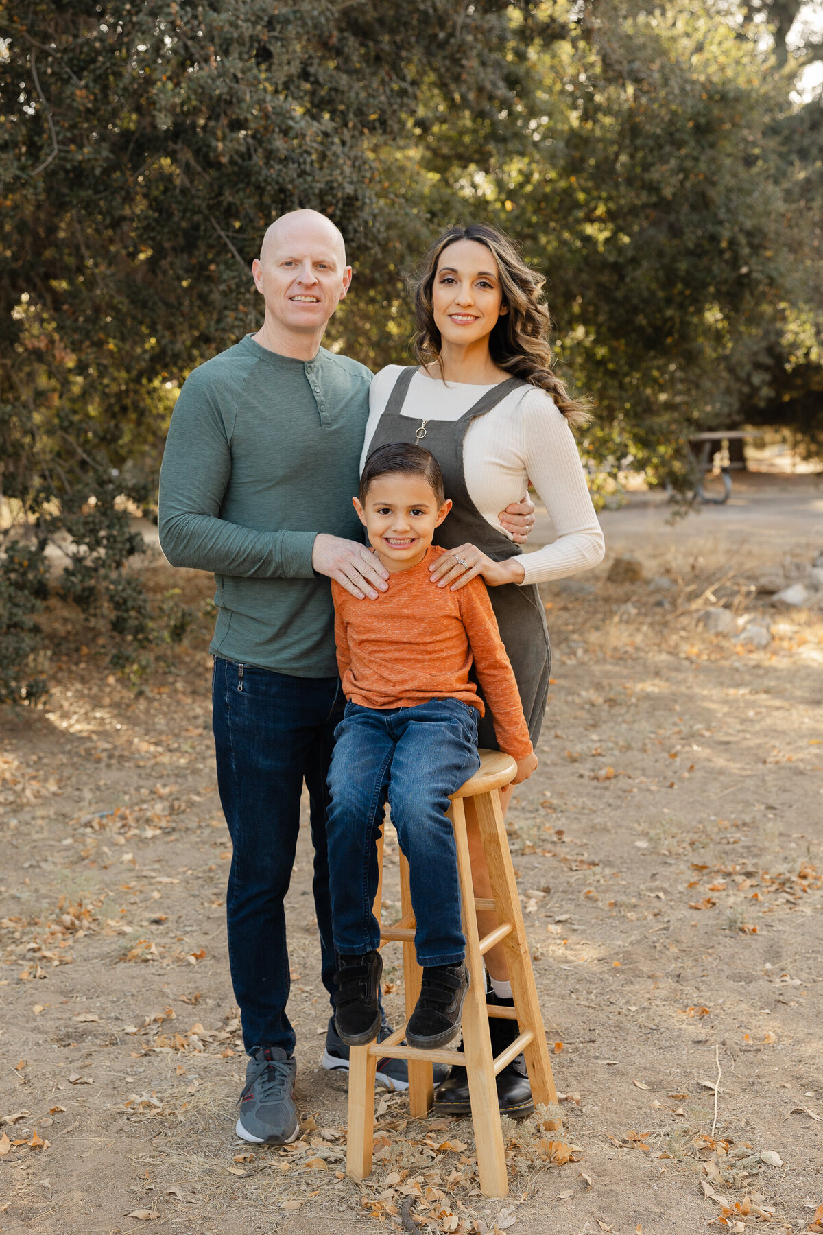 Parents with two sons standing together outdoors in fall colors. Photographed by Yucaipa family photographer Kaitlyn Dawn Photography.